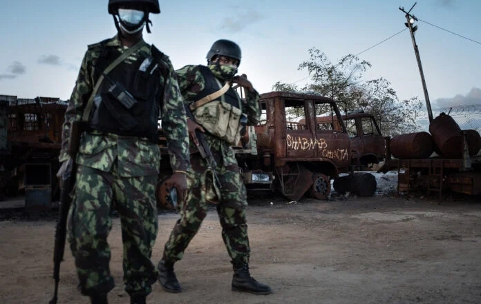 TOPSHOT - Mozambican soldiers patrol in front of a burned truck carrying the inscription "Shabaab Chinja" referring to the jihadist group in Mocimboa da Praia, on September 22, 2021. - Since July 2021 a contingent of a thousand Rwandan soldiers and policemen is deployed to Mozambique to fight insurgents that were terrorising populations. The Rwanda Defence Forces (RDF) declared few victories among which the liberation of Mocimboia Da Praia which was occupied by jihadist for almost a year. (Photo by Simon WOHLFAHRT / AFP)
