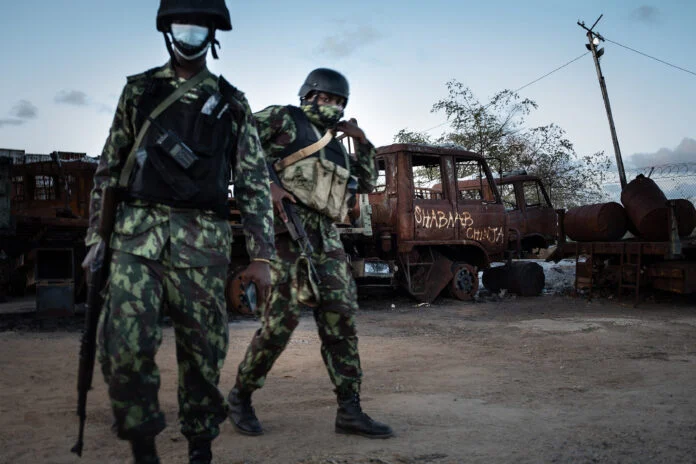 TOPSHOT - Mozambican soldiers patrol in front of a burned truck carrying the inscription "Shabaab Chinja" referring to the jihadist group in Mocimboa da Praia, on September 22, 2021. - Since July 2021 a contingent of a thousand Rwandan soldiers and policemen is deployed to Mozambique to fight insurgents that were terrorising populations. The Rwanda Defence Forces (RDF) declared few victories among which the liberation of Mocimboia Da Praia which was occupied by jihadist for almost a year. (Photo by Simon WOHLFAHRT / AFP)
